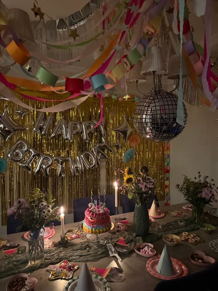 Birthday dinner party with a disco ball, gold fringe backdrop, streamers and handmade paper chains