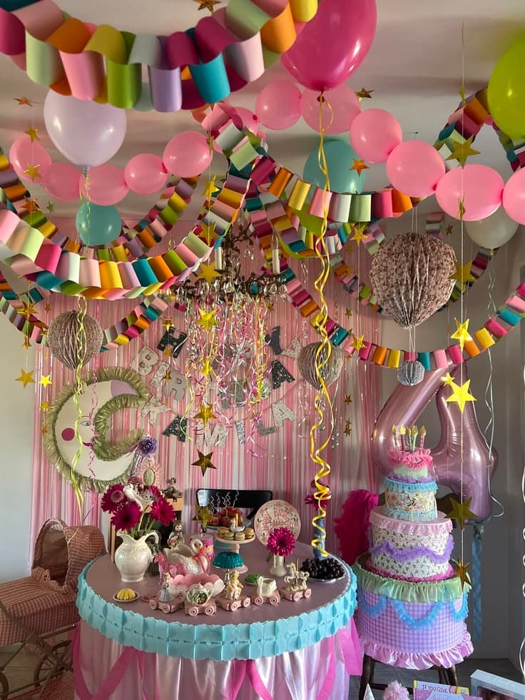 Pastel birthday party with handmade paper chain garlands, balloons and a ruffled dessert table