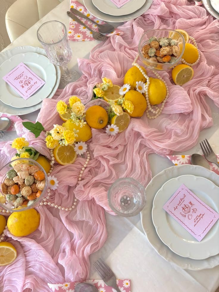 Lemon and daisy tablescape on a pink gauze runner with pearl garlands